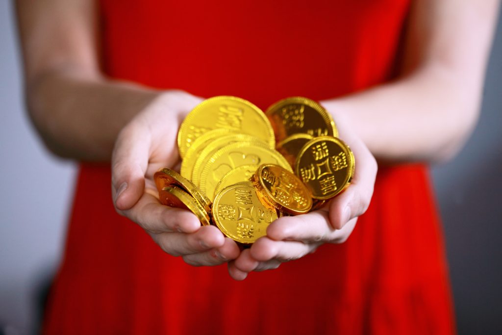 women in red dress holding gold bars and coins